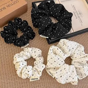 Detailed view of French style floral pattern scrunchies in black and cream fabric