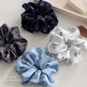 Detail of four striped fabric scrunchies featuring blue bow patterns in soft pastel colors