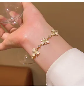 Close-up of elegant copper bracelet with oval cat-eye stone flowers and sparkly zircons