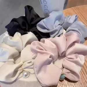 Close-up of satin scrunchies in assorted colors with elegant pearl pendant details