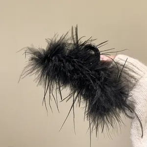 Elegant black feather hair claw clip for women's bun hairstyles.