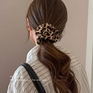 Rear view detail of a classic leopard print fabric scrunchie on brown hair
