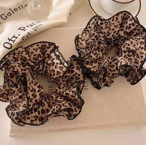 Set of two vintage leopard print fabric scrunchies displayed on aesthetic props
