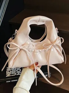 Elegante bolso de mano en charol rosa claro con lazos decorativos y asa superior