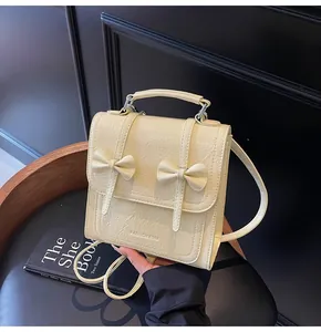 Detailed shot of a cream bow backpack featuring textured faux leather and top handle.