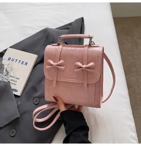 Detailed view of pink textured bow-tie backpack showing fabric and embossed lettering