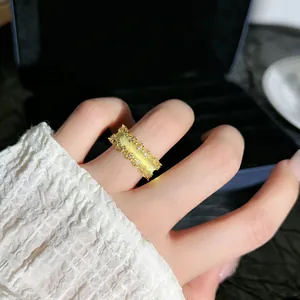 Primo piano di un anello in oro spazzolato con bordi in pizzo e cristalli al dito