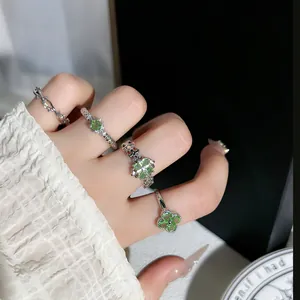 Detaillierte Nahaufnahme von mintgrünen Kleeblatt- und Dornenringen auf einem Finger