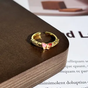 Nahaufnahme eines eleganten vergoldeten Rings mit einem rosa emaillierten Schmetterling