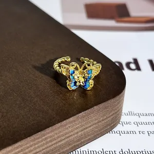 Detaillierte Makroansicht eines goldenen Schmetterlingsrings mit blauem Emaille-Verlauf-Detail