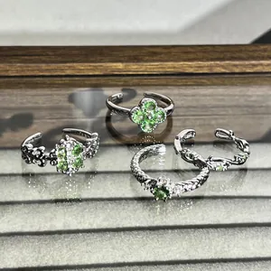 Detailansicht von vier silberfarbenen Ringen mit mintgrünen Kleeblattmotiven und Struktur