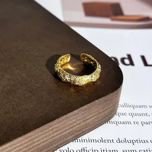 Makro-Detail eines vergoldeten offenen Rings mit kunstvoller Kristall-Pavé-Textur