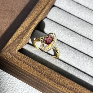 Detailaufnahme eines Vintage-Rings mit rotem Edelstein und ovalem Diamanthalo-Design