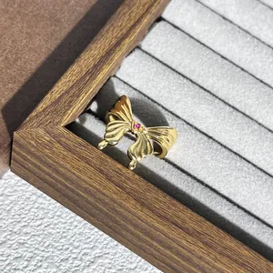 Detailansicht eines eleganten goldenen Schmetterlingsrings mit rotem Stein in Box