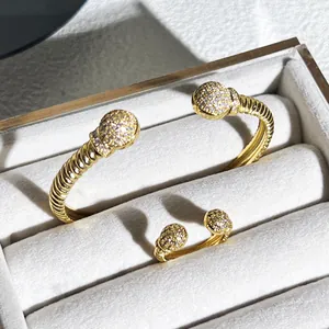 Dettaglio ravvicinato di bracciale rigido e anello intrecciati d'oro con zirconi