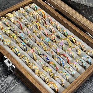 Detalle de anillos de esmalte de colores con diseños vintage de flores y mariposas en caja.
