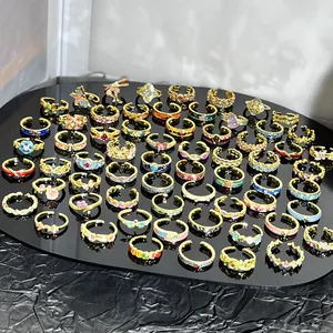 Amplia colección de anillos florales de esmalte de colores sobre una superficie negra brillante