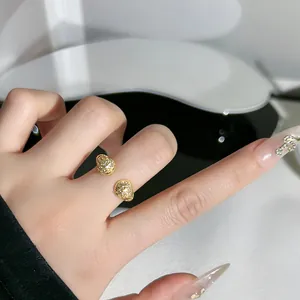 Primo piano di un anello aperto dorato con sfere in micro-pavé di cristalli al dito