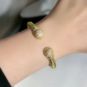 Vista dettagliata del bracciale rigido aperto in cavo d'oro intrecciato con cristalli
