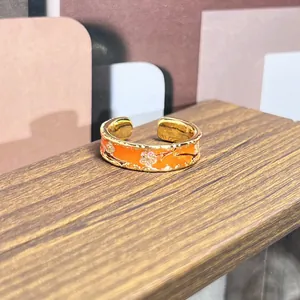 Primer plano detallado de un anillo vintage de esmalte naranja con flores rosas.