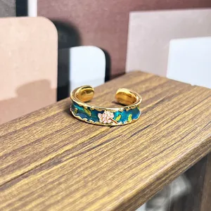 Vista macro de anillo de esmalte vintage con patrón floral rosa en fondo azul