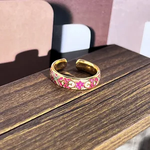 Vista detallada macro de un anillo de flor de esmalte vintage con acabado rosa y dorado.