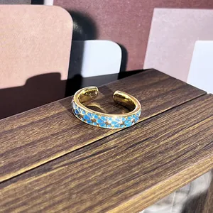 Vista detallada de un anillo retro dorado con patrones florales de esmalte azul