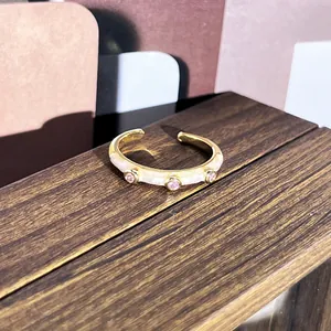 Detalle de anillo vintage de esmalte dorado con circonitas sobre soporte madera