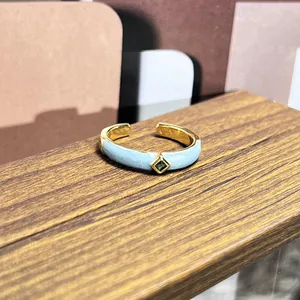 Primer plano detallado de un anillo vintage de esmalte azul claro con gema verde cuadrada.