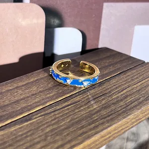 Vista macro de un anillo dorado estilo palacio con esmalte azul y piedras brillantes