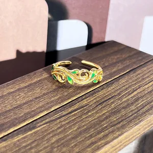 Primer plano de un anillo dorado vintage ajustable con diseño de hojas en esmalte verde