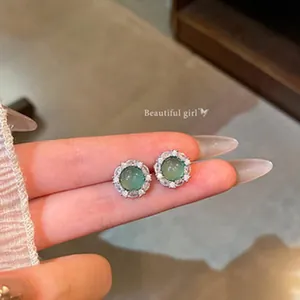Close-up detail of green round gemstone stud earrings with sparkling micro-pave zircon border
