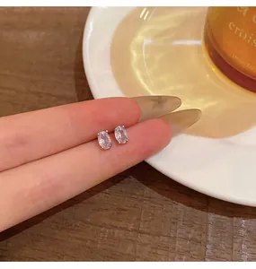 Detail of dainty silver-tone stud earrings featuring oval-cut clear cubic zirconia.