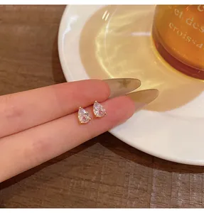 Close-up of elegant pear-shaped zircon stud earrings in a warm cafe setting
