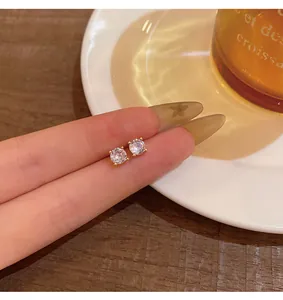 Macro view of dainty cubic zirconia stud earrings in a four-prong gold setting
