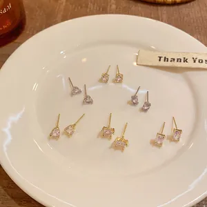Assorted Korean style CZ stud earrings in heart, oval, and pear shapes on white plate