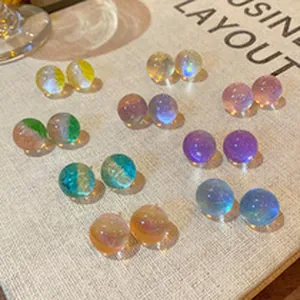 Close-up of colorful translucent iridescent ball stud earrings on textured fabric