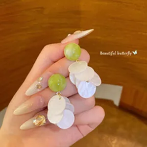 Close-up of green bead earrings with white disc dangles for summer style