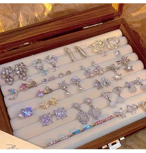 Detailed macro view of luxury zircon earring collection inside a wooden jewelry box display