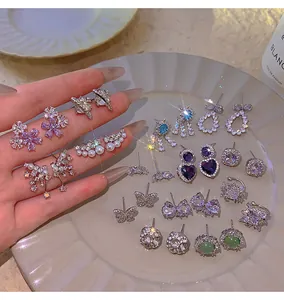 Detail shot of various elegant Korean zircon earrings and heart studs on a plate.