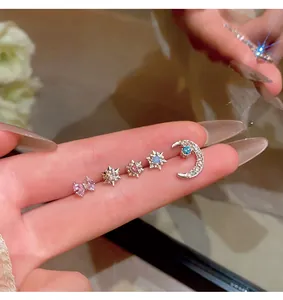 Close-up of five dainty zircon stud earrings in moon, star and butterfly shapes.