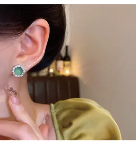 Detailed close-up view of an elegant green zircon stud earring worn on an Asian model