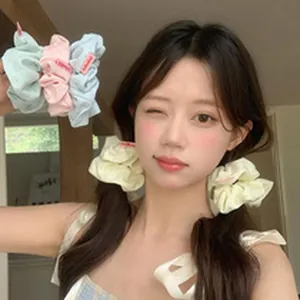 Elastici per capelli in pizzo oversize indossati da una modella con dei codini.