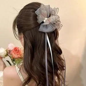 Vista posteriore di un elegante fiocco in pizzo grigio con perle e nastri sui capelli