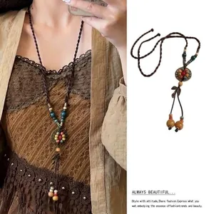 Detail view of ethnic style long necklace with ceramic beads and feather pendant