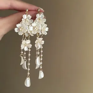 Macro detail of elegant white floral tassel earrings with pearls and hanging petals
