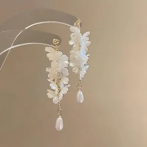 Detailed view of elegant white flower petal tassel earrings with pearls and gold accents