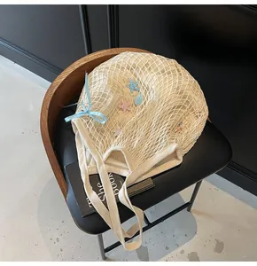 Detailed view of beige hollow mesh tote bag with starfish and blue ribbon charms