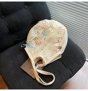 Macro detail of beige hollow mesh tote bag with pastel starfish charms and blue ribbon