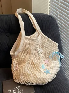 Large cream mesh tote bag with starfish charms and blue ribbon displayed on a chair